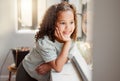 Little girl dreaming of playing outside in the sun after lockdown, smiling and looking out of a window. Small, cute