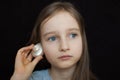 Little girl is dreaming about the summer trip to the ocean and listening to a white shell to hear a sea sound on black Royalty Free Stock Photo