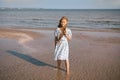 little girl in dress on the beach with developing long blond hair in the wind and looking on the sea Royalty Free Stock Photo