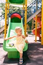 Little girl in a dress climbs down the childrens slide, turning her head to the side Royalty Free Stock Photo