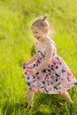 A little girl in dress with pigtails run in a green field, light of warm rays of the sun Royalty Free Stock Photo