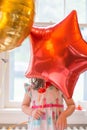 Little girl in dress playing with her colorful birthday balloons