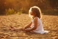 Little girl in dress sitting on the sand