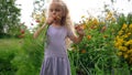 Little girl in dress with uproot carrots in her hands look at camera and smiling