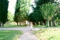 Little girl in a dress walks along a gravel path in a green park Royalty Free Stock Photo