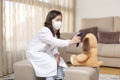 Little girl dressed as a doctor and medical mask taking the temperature of a teddy bear with an infrared thermometer. She is at Royalty Free Stock Photo