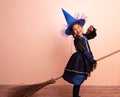 Little girl dressed as a witch holding a broom