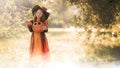 Little girl dressed as a witch with a pumpkin in her hands in the forest in the fog with a copy space, Halloween concept