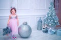 Little girl dressed in beautiful fashion white flower dress posing near Christmas tree Royalty Free Stock Photo