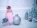 Little girl dressed in beautiful fashion white flower dress posing near Christmas tree Royalty Free Stock Photo