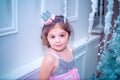 Little girl dressed in beautiful fashion white flower dress posing near Christmas tree Royalty Free Stock Photo