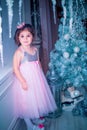 Little girl dressed in beautiful fashion white flower dress posing near Christmas tree Royalty Free Stock Photo