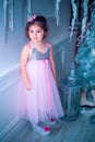 Little girl dressed in beautiful fashion white flower dress posing near Christmas tree Royalty Free Stock Photo