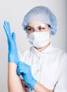 Little girl dressed in medical clothes pulls into the hands medical gloves Royalty Free Stock Photo