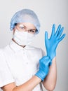 Little girl dressed in medical clothes pulls into the hands medical gloves Royalty Free Stock Photo