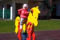 A little girl dressed in a pink jacket is sitting on a yellow toy horse. Baby plays on the playground, sits on the rocking chair Royalty Free Stock Photo