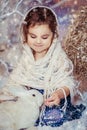 Little girl dressed in vintage winter tradition against artificial snow and forest background