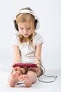 Little girl dressed in white with headphones playing