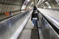 Little girl dressed in winter clothing on a moving walkway in the Tube London England 01 - 10 - 2018