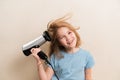 little girl dries her hair with a hair dryer with a comb attachment. Royalty Free Stock Photo