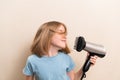 little girl dries her hair with a hair dryer with a comb attachment. Royalty Free Stock Photo