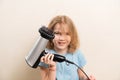 little girl dries her hair with a hair dryer with a comb attachment. Royalty Free Stock Photo