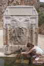 Little girl drinking on hands at Palomas Pillar fountain, Hornachos, Spain