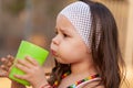 Little girl drinking water from a glass in the park Royalty Free Stock Photo