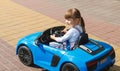 A Little Girl Is Driving A Battery-Powered Car In An Open-Air Amusement Park. A cute child is sitting in his blue toy car. The con Royalty Free Stock Photo