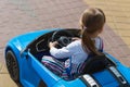 A little girl driving a blue electric car in an amusement park. A cute little racer Drives A Children`s Car. The concept of a happ Royalty Free Stock Photo