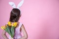 Little girl with easter bunny ears holding a bouquet of spring flowers back view copy space Royalty Free Stock Photo
