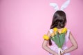 Little girl with easter bunny ears holding a bouquet of spring flowers back view copy space Royalty Free Stock Photo