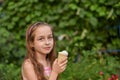 Little girl eat ice cream at an outdoor In a colorful striped bright dress. Sunny summer, hot weather Royalty Free Stock Photo