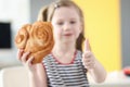 Little girl eating big bun and showing thumb up closeup Royalty Free Stock Photo