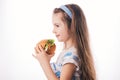 Little girl eating big burger. Kid looking at healthy big sandwich, studio isolated on white background