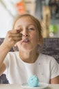 Little girl eating blue ice cream in a cafe. Girl delighted with ice cream. Adorable little girl eating ice cream at summer.