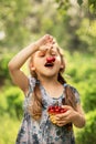 Little girl eating cherries from a basket on nature Royalty Free Stock Photo