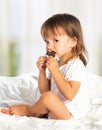Little girl eating chocolate candy in bed Royalty Free Stock Photo