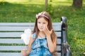 Little girl eating cotton candy sitting on a bench in the park summer Royalty Free Stock Photo
