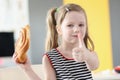 Little girl eating delicious sweet bun and showing thumb up Royalty Free Stock Photo