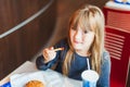 Little girl eating fast food in a cafe