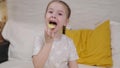 little girl eating golden potato chips sitting on the bed in the bedroom, fast food for kid, unhealthy baby food Royalty Free Stock Photo