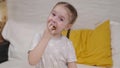 little girl eating golden potato chips sitting on the bed in the bedroom, fast food for kid, unhealthy baby food Royalty Free Stock Photo