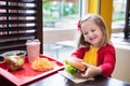 Little girl eating a hamburger in fast food restaurant Royalty Free Stock Photo