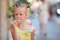 Little girl eating ice-cream outdoors at summer. Cute kid enjoying real italian gelato near Gelateria in Rome Royalty Free Stock Photo