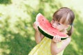 Little girl eating a juicy watermelon in the sunny summer garden Royalty Free Stock Photo