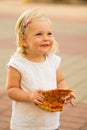 A little girl is eating a large slice of pizza, getting dirty. Street fast food