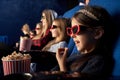 Little girl eating popcorn, watching cartoon in cinema.