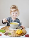 Little Girl Eating Pumpkin Cream-Soup at Home