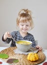 Little Girl Eating Pumpkin Cream-Soup at Home